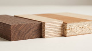Three wood samples side by side showing their cut edges — solid walnut with continuous grain, plywood with stacked layered plies, and particleboard with a thin veneer over a flaky core — illustrating solid wood vs plywood vs veneer