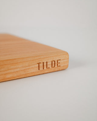 Wooden cutting board with 'TILDE' engraving on a light background