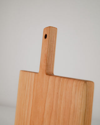 Wooden cutting board with handle on a light gray background