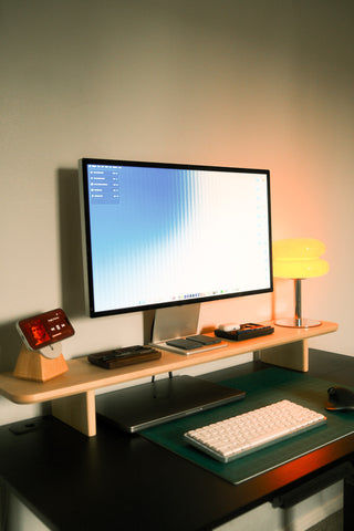 Maple Monolith Desk Shelf supporting a monitor and yellow mushroom lamp on a standing desk, with MagSafe stand and keyboard.