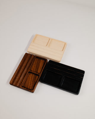 Monolith Desk Tray shown in all three wood options — walnut, maple, and black oak stacked
