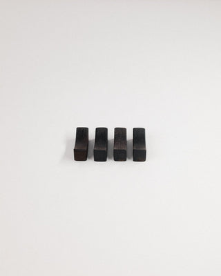 Four Indian laurel chopstick rests in a row on a light gray background