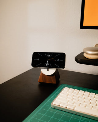 Solid walnut wood iPhone MagSafe charger stand side view showing grain detail on a desk with monitor and keyboard