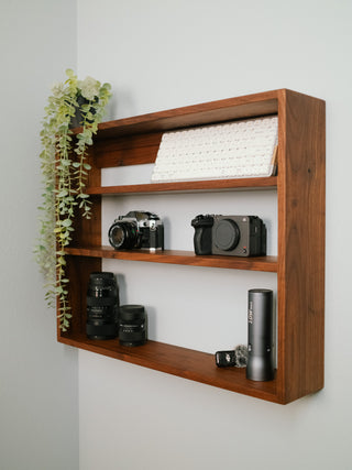 Monolith Wall Shelf displaying camera lenses and photography gear on solid hardwood tiers