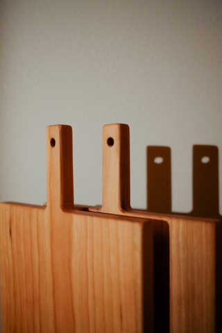Wooden cutting board with handles on a neutral background